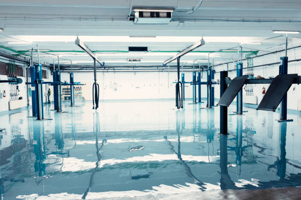 Wide shot of an empty car repair garage with hydraulic lifts and a shiny epoxy floor